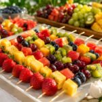 Colorful fruit skewers for parties on a serving tray with strawberries, grapes, pineapple, kiwi, and blueberries