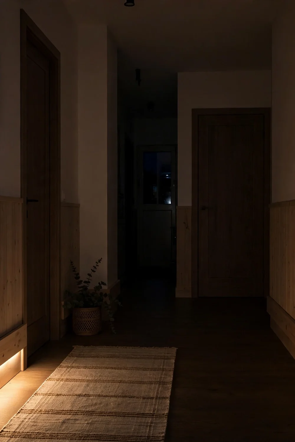 Hallway at night with warm LED light glowing from behind a floating baseboard