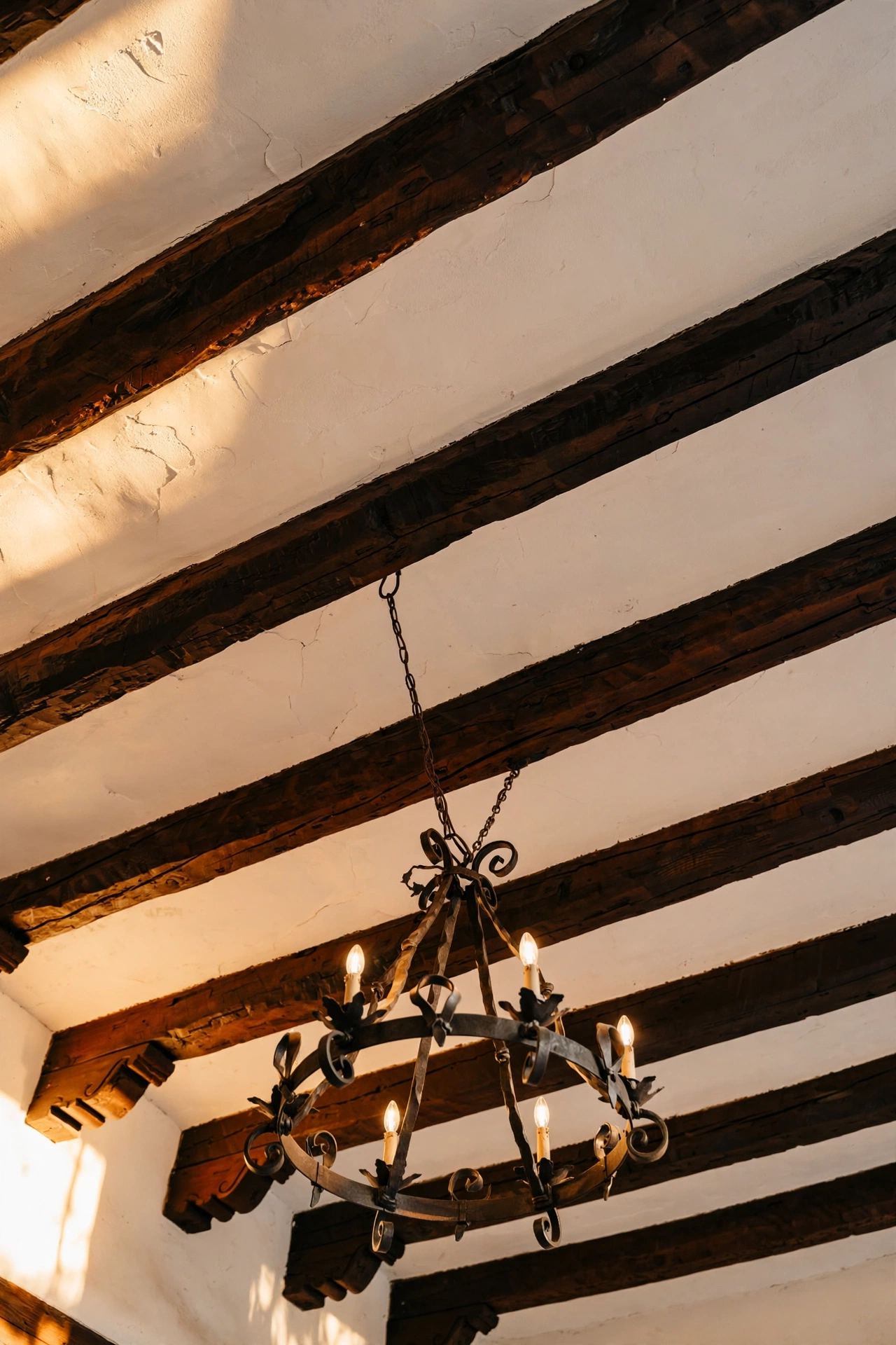 Living room ceiling with exposed dark wooden vigas beams and wrought iron chandelier