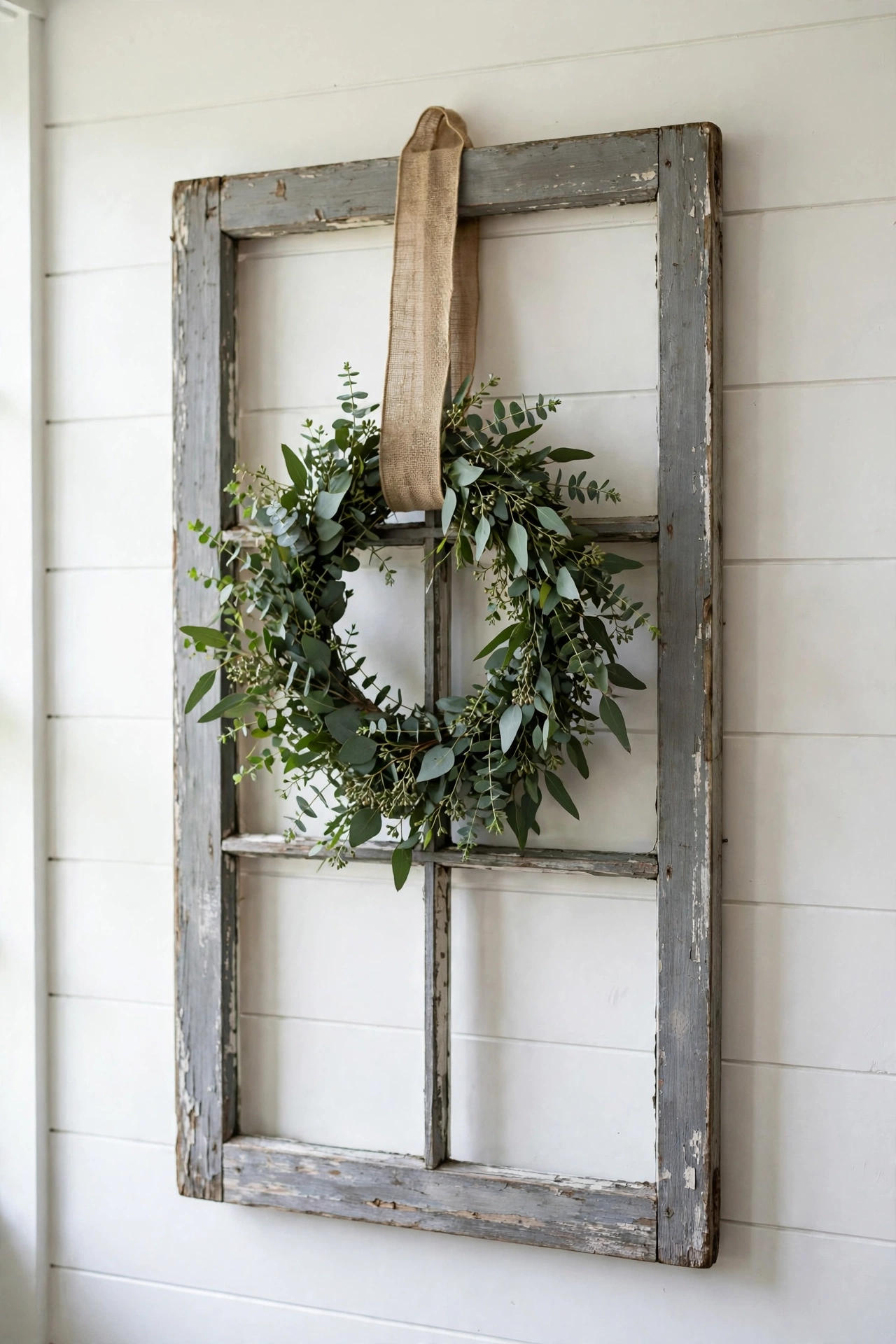 Weathered window frame with a green eucalyptus wreath hanging in the center